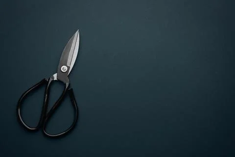 Pair of sharp scissors on dark background, top view. Space for text Stock Photos