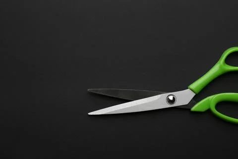 Pair of sharp scissors on dark background, top view. Space for text Stock Photos