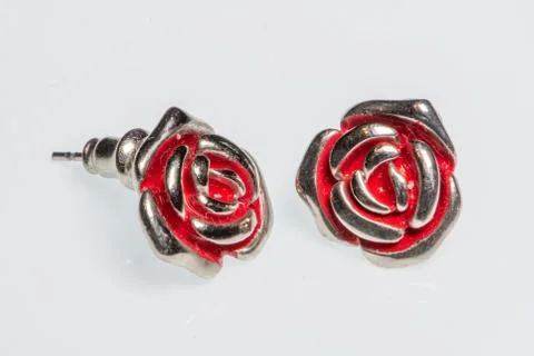 Pair of silver earrings in the shape of a rose with red details Stock Photos
