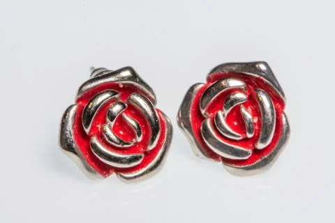 Pair of silver earrings in the shape of a rose with red details Stock Photos