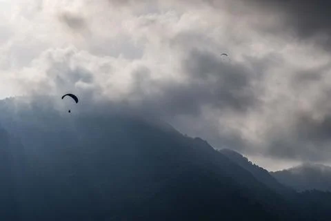 A pair of skydivers are flying through the air above a mountain range Fotos Stock