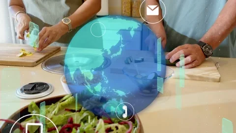 Pair slicing vegetables in kitchen, tech globe with icons appearing and covering Stock Footage 333463250