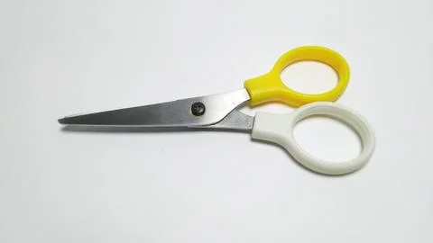 A pair of small craft scissors with yellow and white plastic handles. Stock Photos