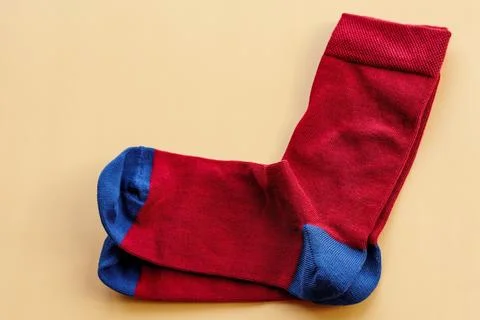 A pair of socks on a beige background. Red and blue knitted socks. Stock Photos
