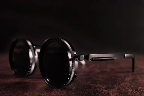 A pair of sunglasses on a table with a dark background Stock Photos