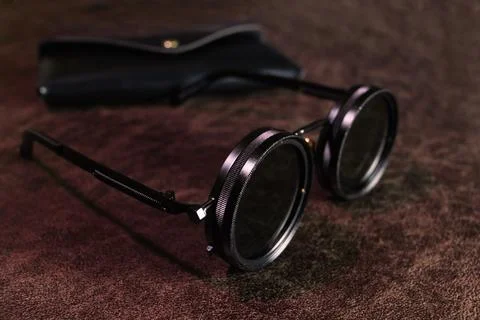 A pair of sunglasses on a table with a dark background Stock Photos