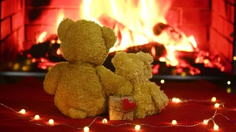 Pair of teddy bears are sitting hugging against the background of the fireplace Stock-Footage 168387617