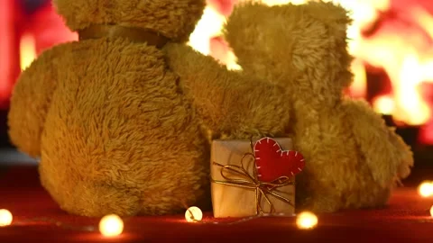 Pair of teddy bears are sitting hugging against the background of the fireplace Stock-Footage 168387642