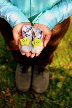 A pair of tiny baby socks held gently in a man's hands Stock Photos