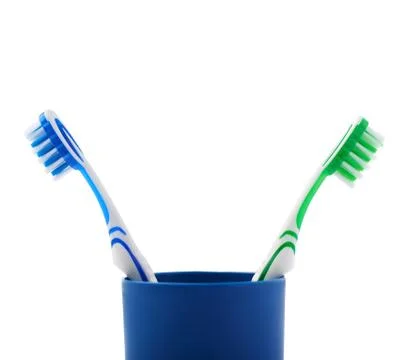 Pair of toothbrushes in blue plastic cup isolated over white background Fotos Stock