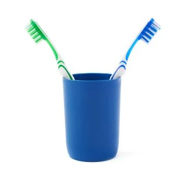 Pair of toothbrushes in blue plastic cup isolated over white background Fotos Stock