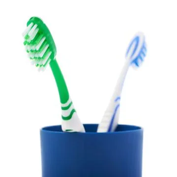 Pair of toothbrushes in blue plastic cup isolated over white background Fotos Stock
