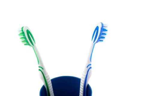 Pair of toothbrushes in blue plastic cup isolated over white background Fotos Stock
