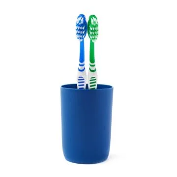 Pair of toothbrushes in blue plastic cup isolated over white background Fotos Stock