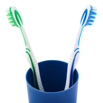 Pair of toothbrushes in blue plastic cup isolated over white background Fotos Stock
