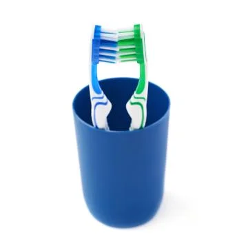 Pair of toothbrushes in blue plastic cup isolated over white background Fotos Stock