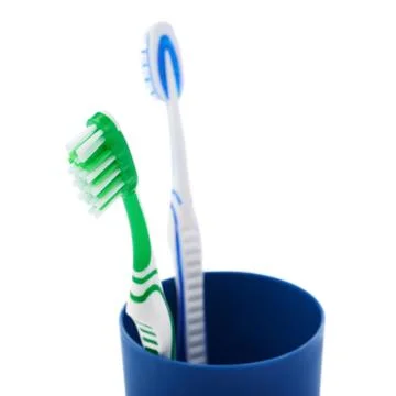 Pair of toothbrushes in blue plastic cup isolated over white background Fotos Stock