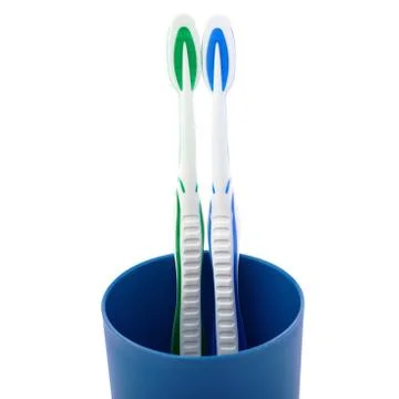 Pair of toothbrushes in blue plastic cup isolated over white background Fotos Stock