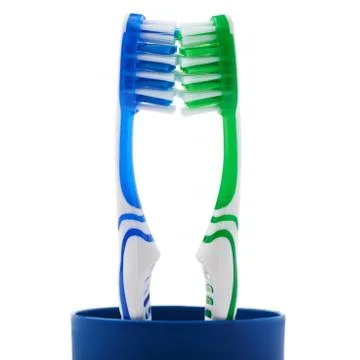 Pair of toothbrushes in blue plastic cup isolated over white background Fotos Stock