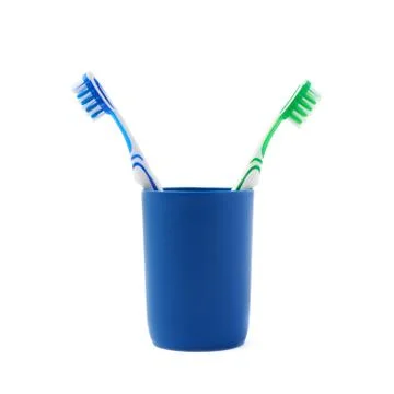 Pair of toothbrushes in blue plastic cup isolated over white background Fotos Stock