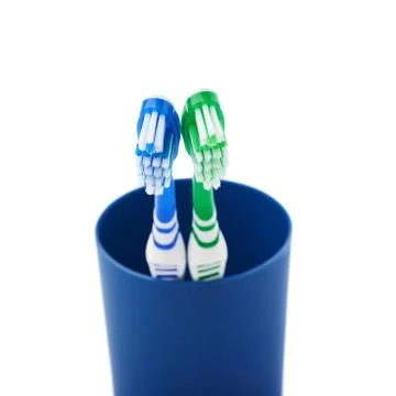 Pair of toothbrushes in blue plastic cup isolated over white background Fotos Stock
