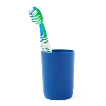 Pair of toothbrushes in blue plastic cup isolated over white background Fotos Stock