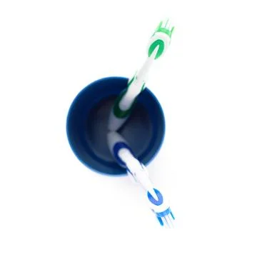 Pair of toothbrushes in blue plastic cup isolated over white background Fotos Stock