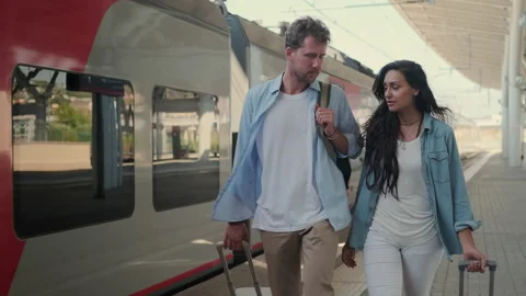 Pair of travellers is walking to train, rolling suitcase Stock Footage 148343900