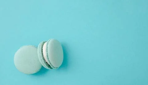Pair of turquoise macarons on solid turquoise background, teal monochrome f.. Fotos Stock