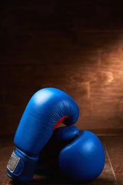 Pair of the two red boxing gloves lie on wooden table against wooden background. Stock Photos