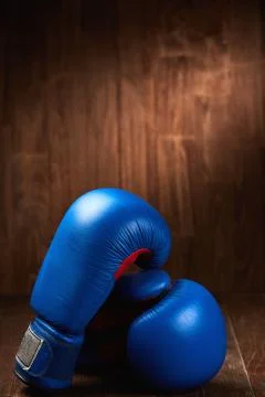 Pair of the two red boxing gloves lie on wooden table against wooden background. Stock Photos