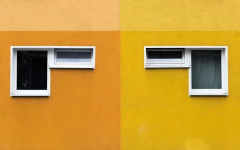 A pair of two windows on a yellow and orange facade Stock Photos