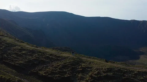 Pair walking the narrow track around the caldera of Faial. Azores, Portugal Stock Footage 118016379