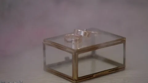 A pair of wedding rings sitting on top of a glass box in hazy smoke. Stock-Footage 314979325