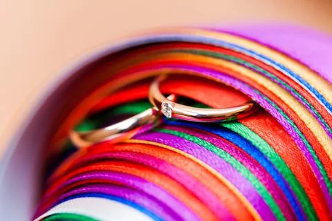 Pair of wedding rings in stack of rainbow colored ribbons. Engagement ring wi 库存照片