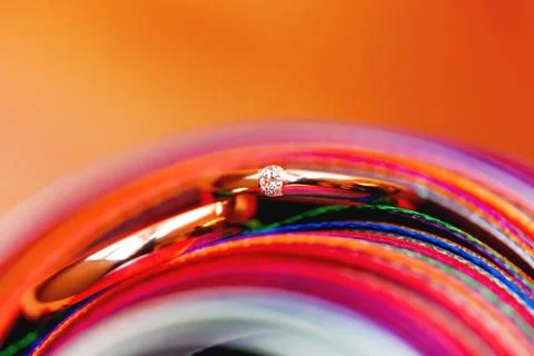 Pair of wedding rings in stack of rainbow colored ribbons. Engagement ring wi Stock Photos