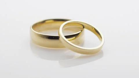 Pair of wedding rings turning on white Stock Footage 33911909