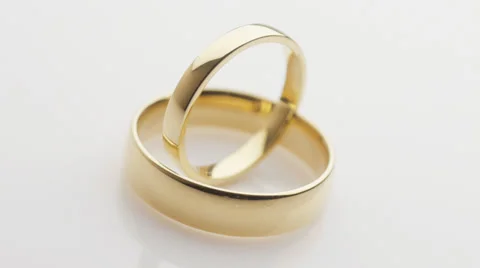 Pair of wedding rings turning on white Stock Footage 33912503