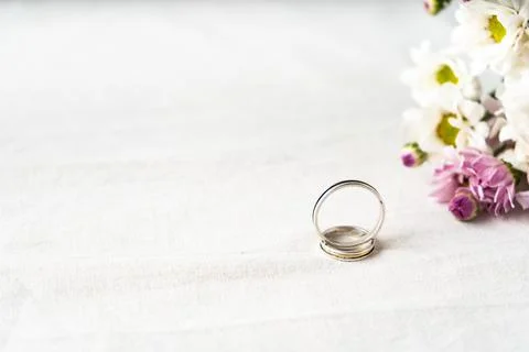 Pair of wedding rings on a white surface with beautiful white and purple flow Stock Photos