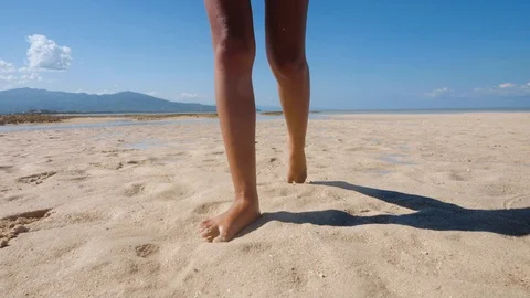 A pair of woman's leg walking on the beach leaving footprints on the sand. Video stock 116405911