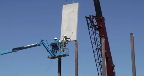 A pair of workers on a telehandler placing a concrete panel for The Trump's Wall Stock Footage 99043268