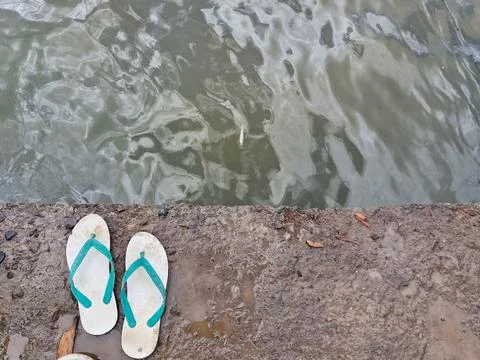 A pair of worn out flip flops on the edge of the pier Stock Photos