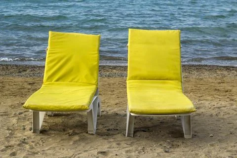 A pair of yellow empty beach loungers on the beach sand near sea Stock Photos