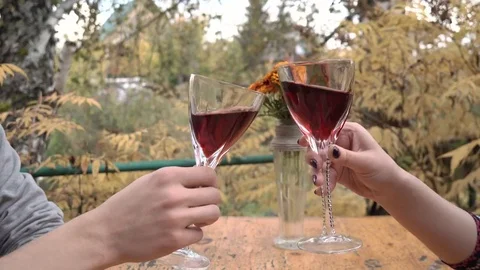 A pair of young people are clinking glasses of red wine and drinking, sitting at Stock Footage 80240775