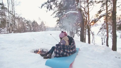 A pair of young people sitting in the winter forest by the fire, picnic Stock Footage 85951243
