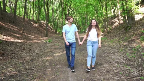Pair young people walking hands in park,smiling,looking at each other,front view Stock Footage 130916280