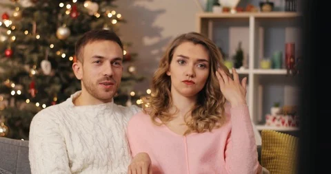 Pair of young pleasant-looking people in love sitting on sofa, watching Stock Footage 85610012
