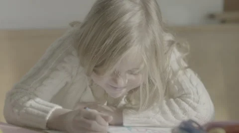 A pair of young sisters sit at the table, carefully coloring inside the lines. Stock Footage 68353093