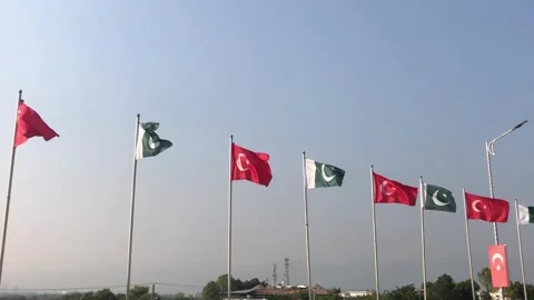 Pakistan and Turkey two flags on flagpoles and blue cloudy sky, waving colorful  Stock Footage 344654961