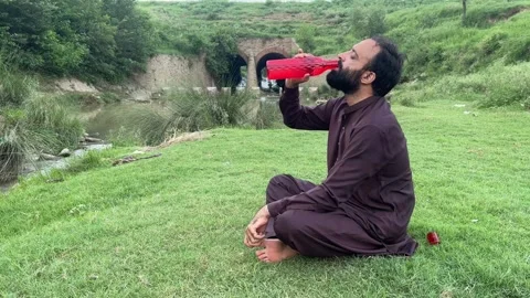 Pakistani Man Drinking Water and Relaxing Near Mountain Stream in Nature Stock Footage 344757927